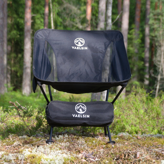 Retkituoli musta, kantokassilla metsämaisemassa, Vaelsin-brändillä.