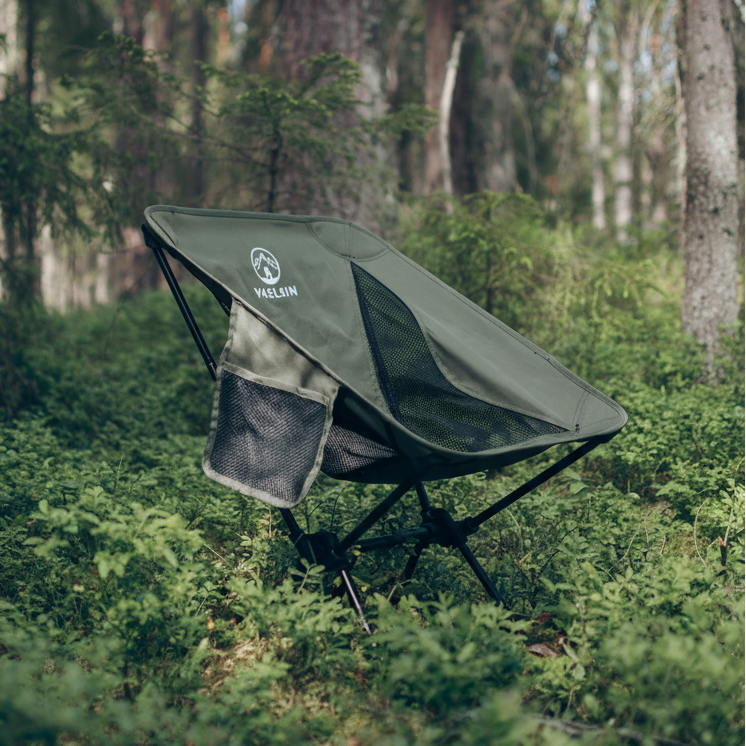 Green camping chair with a brand logo in a forest setting